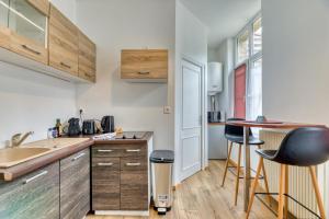 uma cozinha com armários de madeira e bancos de bar em Thomas, F2 moderne au coeur de la Bouille em La Bouille