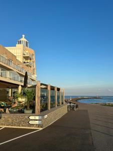 a boardwalk next to a beach with a building at Oosterschelde Lodge met veel privacy en dicht bij het water in Scherpenisse