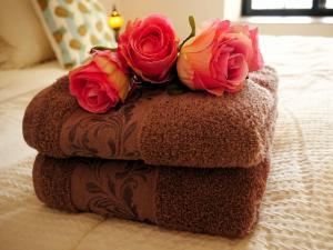 una pila de toallas con rosas en la cama en Encontro no Rio, en Póvoa de Midões
