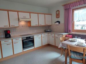 a kitchen with white cabinets and a table and a window at Ferienwohnung Frieda in Sillian