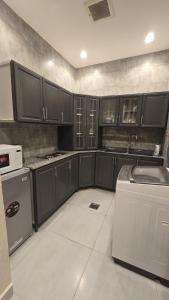 a kitchen with black cabinets and a sink and a dishwasher at Rose in Riyadh
