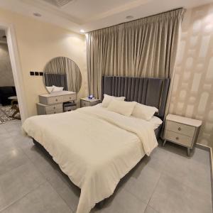 a bedroom with a large white bed and a mirror at Rose in Riyadh