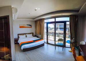 a hotel room with a bed and a large window at Sky Garden Hotel in Coron