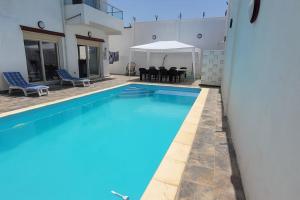 ILY House : Villa de plage avec piscine sans vis-à-vis. في بجاية: حمام سباحة مع طاولة وكراسي في منزل