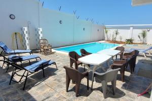 un patio con tavoli e sedie accanto alla piscina di ILY House : Villa de plage avec piscine sans vis-à-vis. a Bejaïa