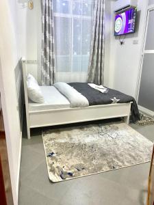 een bed in een kamer met een raam en een tapijt bij DODOMA WHITE HOTEL in Dodoma