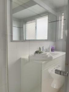 Baño blanco con lavabo y aseo en Chill at Runaway Bay, en Gold Coast