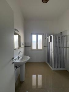ein weißes Badezimmer mit einem Waschbecken und zwei Fenstern in der Unterkunft Aurora e Alba in Casalabate