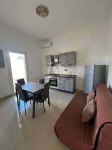 ein Wohnzimmer mit einem Tisch und einer Küche in der Unterkunft Aurora e Alba in Casalabate