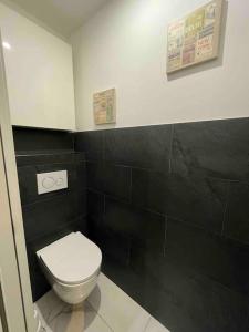 a bathroom with a white toilet and a black wall at Charmant appartement une chambre in Ville-la-Grand