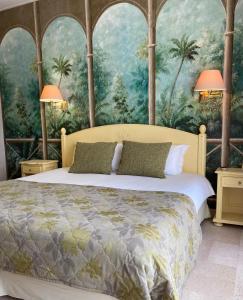 Schlafzimmer mit einem Bett mit einem Gemälde von Palmen in der Unterkunft Hotel Diana in Vence