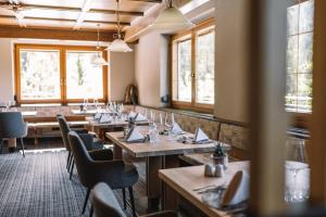 um restaurante com mesas e cadeiras de madeira e janelas em Hotel Mont Floris Obereggen em Obereggen