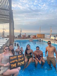 a group of people sitting in a swimming pool at The Point Mancora - Beach Party Hostel in Máncora