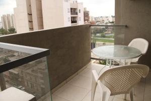 a balcony with a glass table and chairs on a building at Cordoba Rent Centro Avellaneda in Córdoba