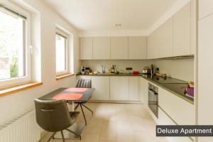 a kitchen with white cabinets and a table with a chair at Rurtal de luxe in Simmerath