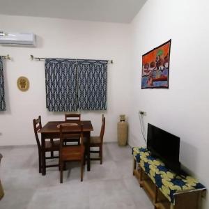 sala de estar con mesa, sillas y TV en Super Appartement à 10mn de la mer, en Cotonou