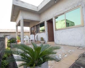 uma casa com um alpendre com cadeiras e uma planta em Super Appartement à 10mn de la mer em Cotonou