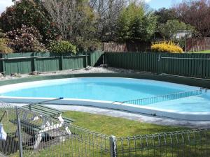 a large swimming pool in a yard with a fence at Maple Lodge Motel in Matamata