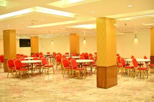 a conference room with tables and red chairs at Dream Inn By Spring Tree in Surendranagar