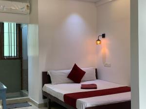 Dormitorio pequeño con cama con almohada roja en FAAZ Residency, en Kozhikode