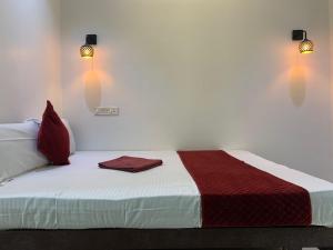 1 cama con manta roja y blanca y 2 luces en FAAZ Residency, en Kozhikode