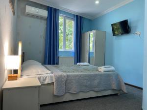 - une chambre bleue avec un lit et un miroir dans l'établissement Hotel Shalimar, à Tbilissi