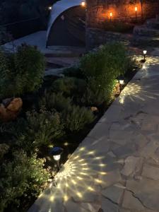 un jardín con plantas y luces por la noche en La Bella Villa, en Melínta