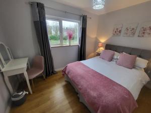 a bedroom with a bed and a desk and a window at Kilronan Holiday Homes in Kilronan