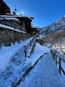 阿拉尼亞瓦爾塞西亞的住宿－Cozy 500 Years Old Walser Home，沿着建筑物旁的雪覆盖的小路行走的人