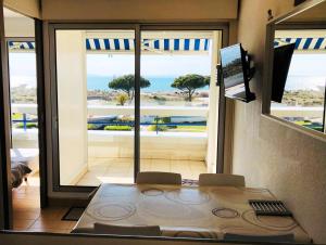 a room with a table and a view of the ocean at CAMARG'Beach Vue mer-Piscines-Plages-Tennis-Parking-4PERS in Le Grau-du-Roi