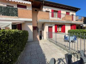 a building with red doors and a fence at Villa Dascia - Agenzia Cocal in Caorle