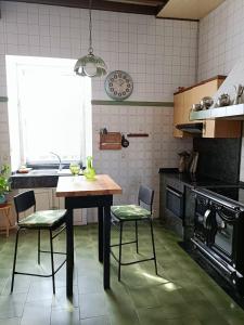 une cuisine avec une table en bois et deux chaises dans l'établissement Casa de piedra en Costa da Morte., à Ponte Do Porto