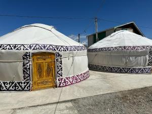 Traditional Yurts - Ulgii Guest House في أولجي: خيامين جيوديسيين مع باب أصفر فيهم