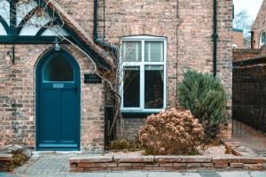 una casa de ladrillo con una puerta azul y una ventana en Rose Cottage, en Brough