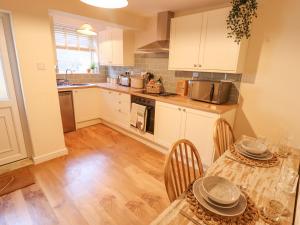 a kitchen with white cabinets and a table with chairs at Rose Cottage in Brough