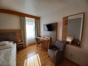 ein Hotelzimmer mit einem Bett, einem Stuhl und einem Schreibtisch in der Unterkunft Hotel Europa in Bonn
