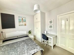 1 dormitorio con cama, escritorio, cama y mesa en Winton house home stay en Bournemouth