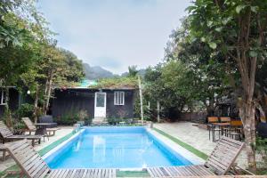 a swimming pool in a yard with chairs and a house at Cat Ba Countryside Homestay in Cat Ba