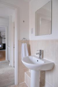 a white bathroom with a sink and a mirror at Sorrel House in Carterton