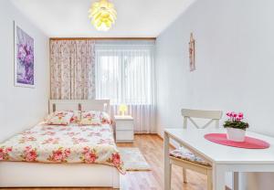 a white bedroom with a bed and a table at Willa Muszelka Przy Morzu in Jastarnia