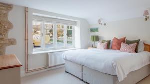 - une chambre avec un grand lit et une fenêtre dans l'établissement A handsome large 9 bedroom 17th Century village house moments from The Cotswold Way offering modern luxury in a peaceful location, à Frocester