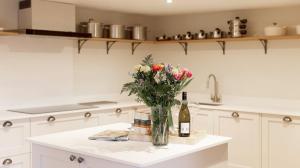 una cocina con un jarrón de flores y una botella de vino en A handsome large 9 bedroom 17th Century village house moments from The Cotswold Way offering modern luxury in a peaceful location en Frocester