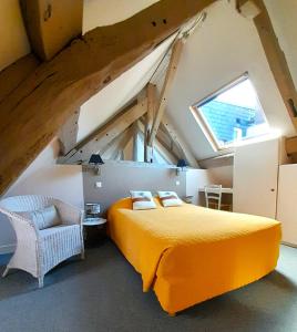 una camera da letto con letto arancione in mansarda di Les Cascades - Hôtel de Charme a Honfleur