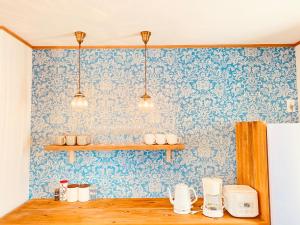 une cuisine avec du papier peint bleu, des étagères et des tasses dans l'établissement hale uka, à Inbu