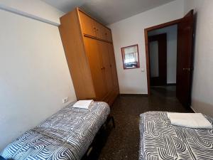 um pequeno quarto com 2 camas e um armário em HABITACIÓN CÉNTRICA EN ACOGEDORA CASA em Valência