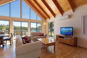 a living room with a flat screen tv and a table at Snug Cove Villas in Eden