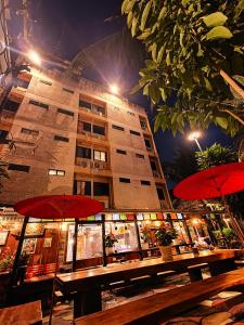 a table with red umbrellas in front of a building at Panda House Chiang Mai in Chiang Mai