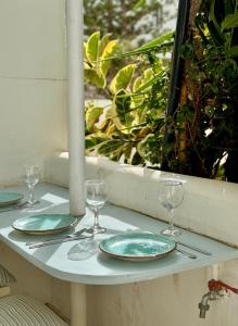 - une table avec des assiettes et des verres à vin sur une fenêtre dans l'établissement Central Cycladic Cove in Naxos Town, à Naxos Chora