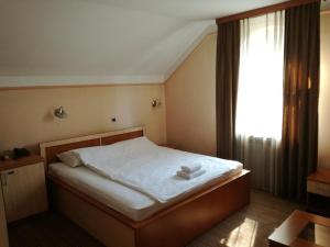 a bedroom with a bed with white sheets and a window at Motel Royal in Tuzla