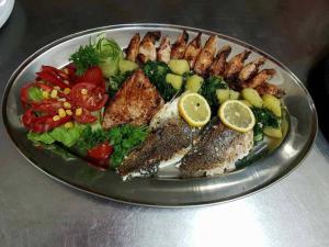 a plate of food with fish and vegetables on a table at Motel Royal in Tuzla